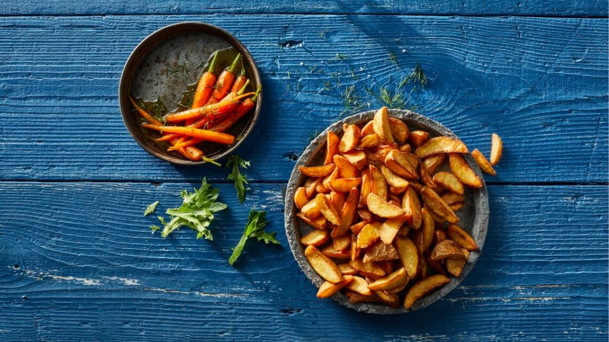 aviko jacket wedges på en tallrik som står på ett blått bord med morötter