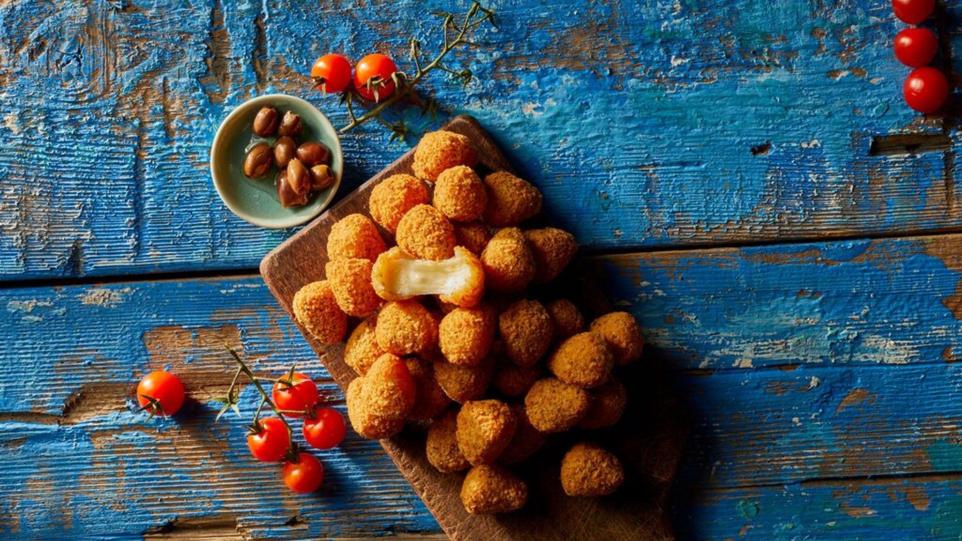 serveringsförslag aviko mozzarella bites på en träbricka som ligger på blå träbakgrund