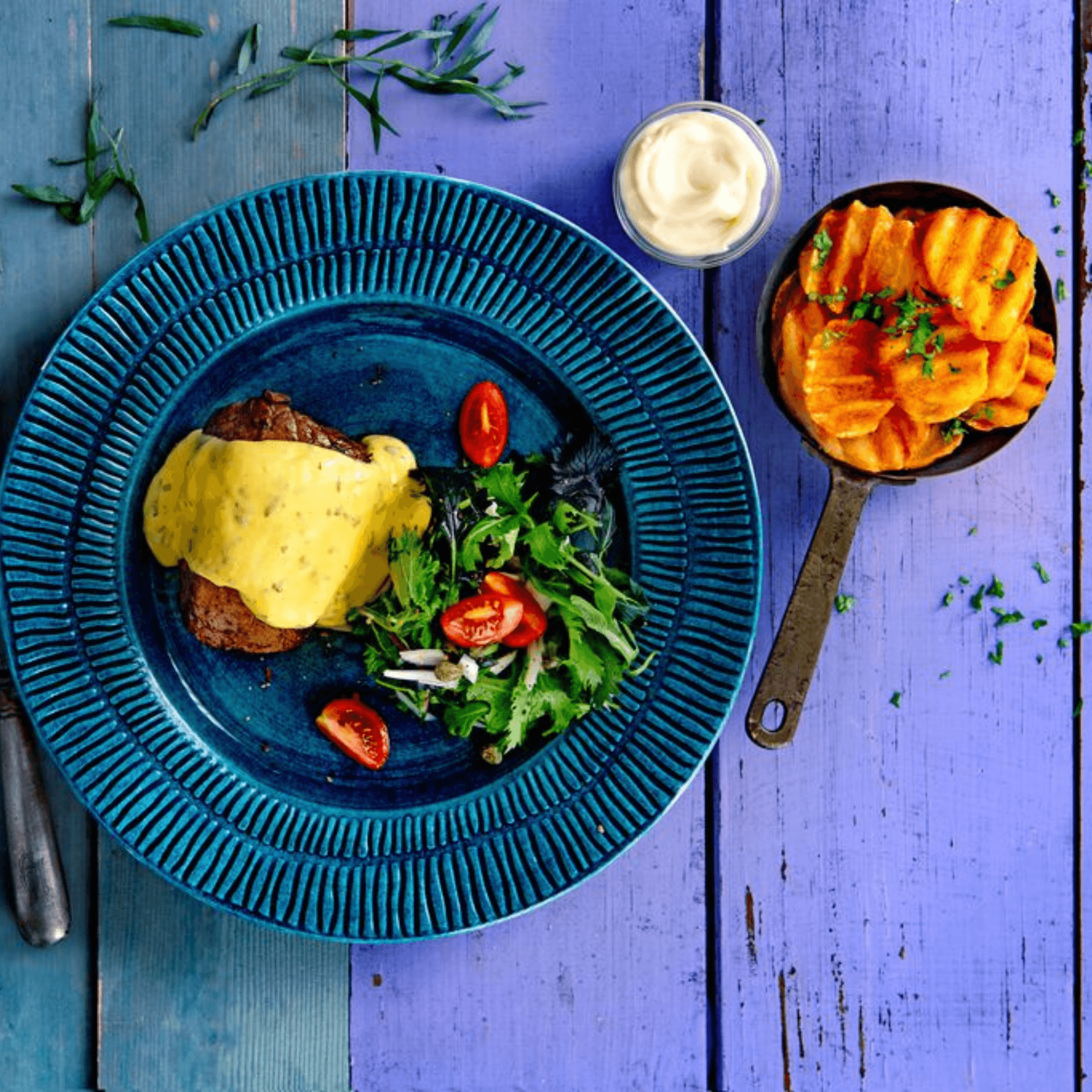 deep crinkle slices potatistillbehör från aviko med kött beasås och sallad på ett blått träbord